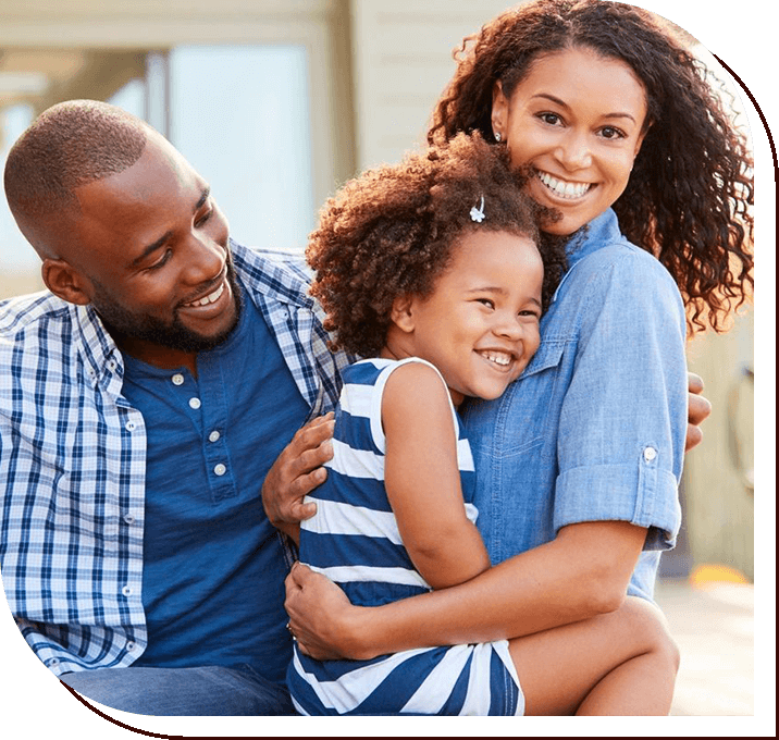 A man and woman hug their daughter while they smile.