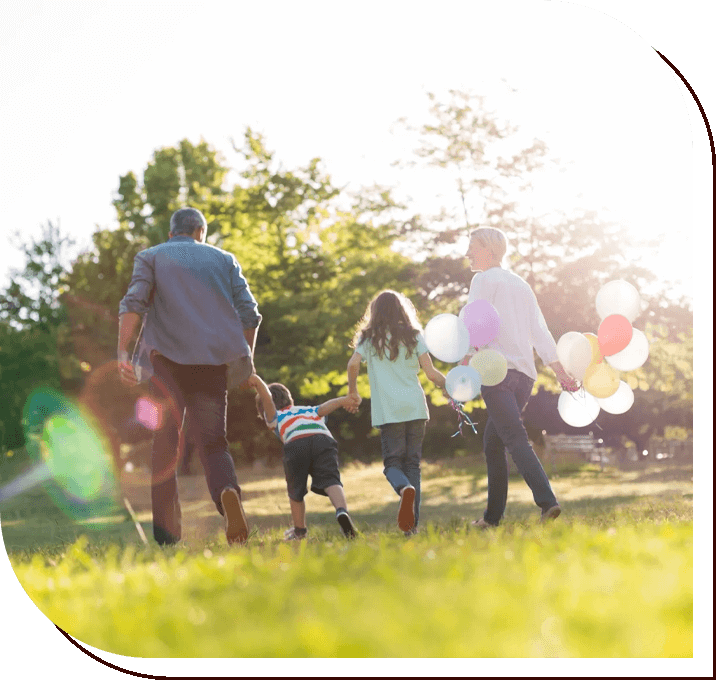 A family walking in the grass holding hands.